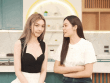 two women are standing next to each other with their arms crossed and one is wearing a black top