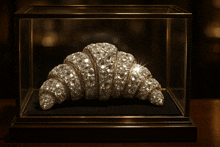 a croissant covered in diamonds in a glass display case
