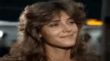 a close up of a woman 's face with long hair and a smile on her face .