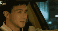 a close up of a man 's face in a car with chinese writing on the bottom