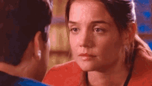 a man and a woman are looking at each other . the woman is wearing a red sweater .
