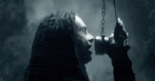 a woman with dreadlocks is holding a chain in her hand and looking up .