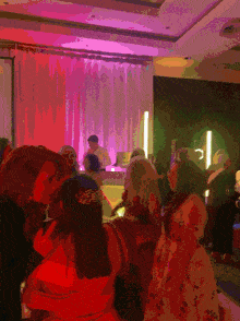 a group of people gathered in a room with purple lights