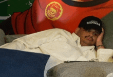 a man is laying on a couch wearing a genmar hat