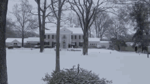 a large white house is covered in snow with trees in the foreground