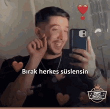 a man is taking a picture of himself in a mirror with hearts around him .