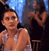a woman in a pink dress is sitting in a chair looking at something