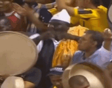 a group of people are playing drums in a crowd and one man is wearing a hat that says ny