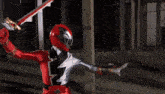 a person in a red and black superhero costume is holding a light beam in their hand .