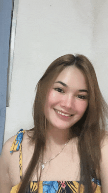 a woman with long hair is smiling and wearing a floral top