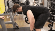 a man wearing a mask is doing exercises with a barbell in a gym .