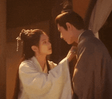 a man and woman are looking at each other and the woman is touching the man 's neck