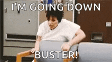 a woman is sitting in a chair with a sign that says `` i 'm going down buster '' .