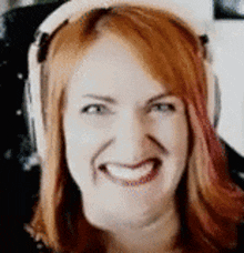 a woman with red hair wearing headphones is smiling .