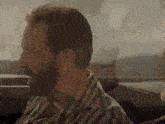 a man with a beard is sitting in the back seat of a car looking out the window .