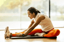 a woman is stretching her legs on a yoga mat