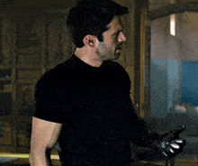 a man in a black shirt holds a gun in his right hand