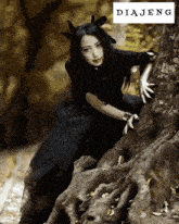 a woman in a black dress is leaning against a tree with the word diajeng behind her