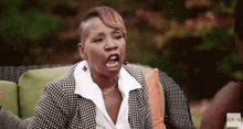 a woman is sitting on a couch making a funny face while talking to a man .