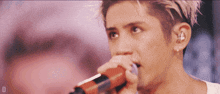 a close up of a man singing into a microphone with the letter d on the bottom right
