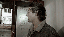 a man in a denim jacket is standing in front of a door with a stained glass window