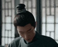 a close up of a man with a bun on his head .