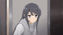 a girl with long black hair and blue eyes is standing in a doorway looking at the camera .