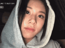 a close up of a woman wearing a grey hoodie with a hood