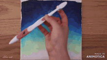 a hand is holding a pen over a canvas with the words made in animatica on the bottom
