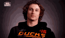 a young man with curly hair is wearing a black hoodie with ducks on it .