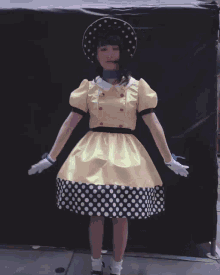 a woman wearing a yellow hat and a dress is dancing