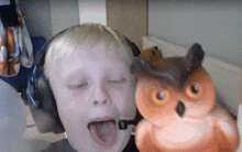 a young boy wearing headphones and a stuffed owl on his shoulder