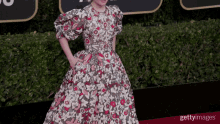 a woman is standing on a red carpet with her hands in her pockets