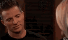 a man and a woman are looking at each other . the man is wearing a black shirt .