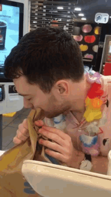 a man wearing a hawaiian lei is eating a bag of food