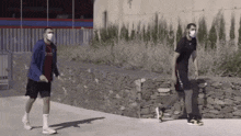 two men wearing face masks are walking down the street