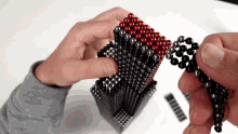 a person is holding a stack of black and red beads in their hands
