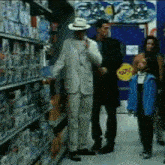 a man in a white suit and hat is standing in a store talking on a phone