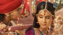 a man and a woman are looking at each other with a sony television ad behind them