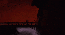 a silhouette of a person holding a sword in front of a red sky