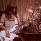 a man with long hair is playing a guitar in front of a drum set that says lg