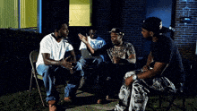 a man wearing a hat with the letter n on it sits in a chair with two other men