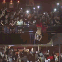 a shirtless man is standing in front of a crowd with his arms in the air
