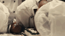 a man in a chef 's hat is laying on a table with a cake on it .