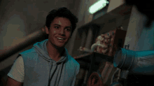 a young man in a grey hoodie is smiling in front of a helmet that says ' ncr ' on it
