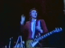 a man playing a guitar on a stage with the letter a in the background