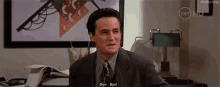 a man in a suit and tie is sitting at a desk and saying bye bye