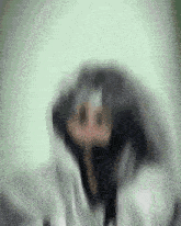 a blurry picture of a person 's face with a hood on .