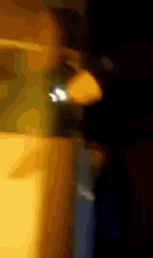 a blurry picture of a person in a dark room with a yellow object in the foreground