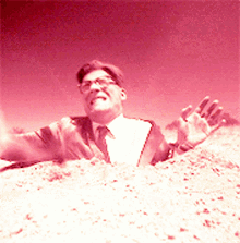 a man in a suit and tie is buried in a pile of sand